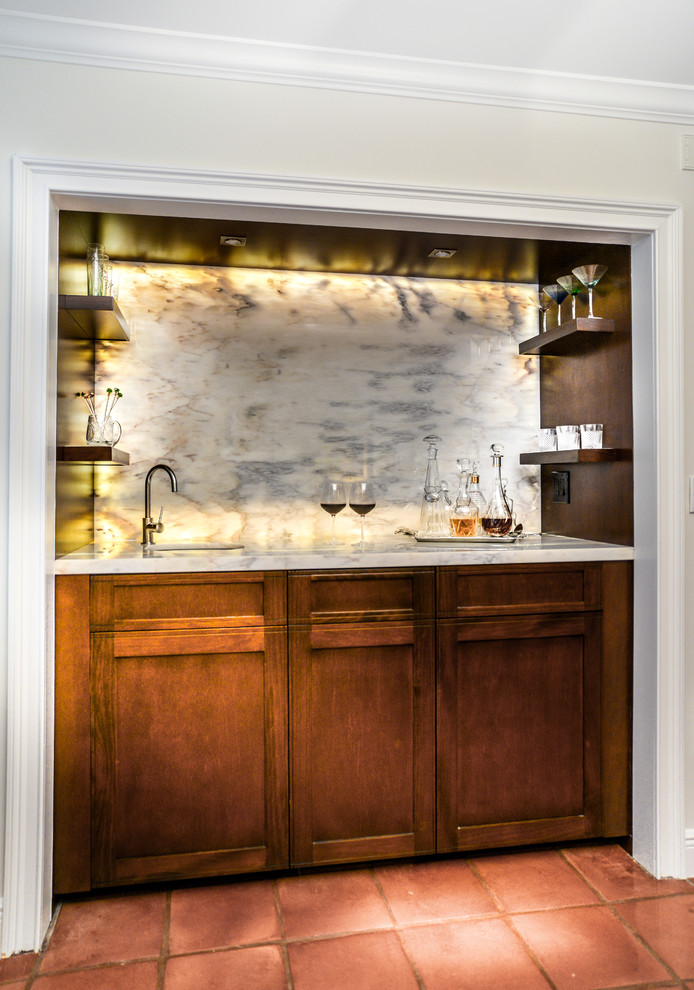 Inspiration for a mid-sized contemporary galley wet bar in Miami with a drop-in sink, shaker cabinets, medium wood cabinets, marble benchtops, grey splashback, stone slab splashback and terra-cotta floors.