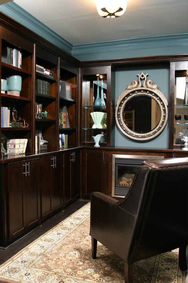 Inspiration for a small traditional home office in Atlanta with a library, blue walls, dark hardwood floors, a standard fireplace, a wood fireplace surround, a built-in desk and black floor.