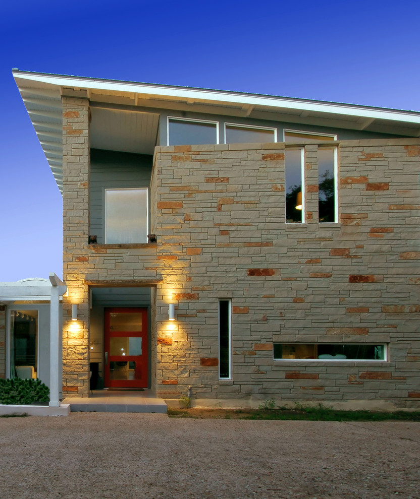 This is an example of a contemporary two-storey exterior in Austin with stone veneer.