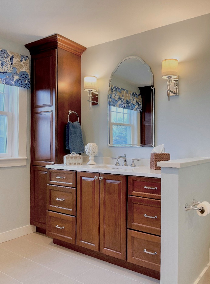 Design ideas for a large traditional master bathroom in Boston with recessed-panel cabinets, medium wood cabinets, a corner shower, a bidet, beige tile, marble, blue walls, porcelain floors, an undermount sink, engineered quartz benchtops, beige floor, a hinged shower door, beige benchtops, a niche, a single vanity and a built-in vanity.