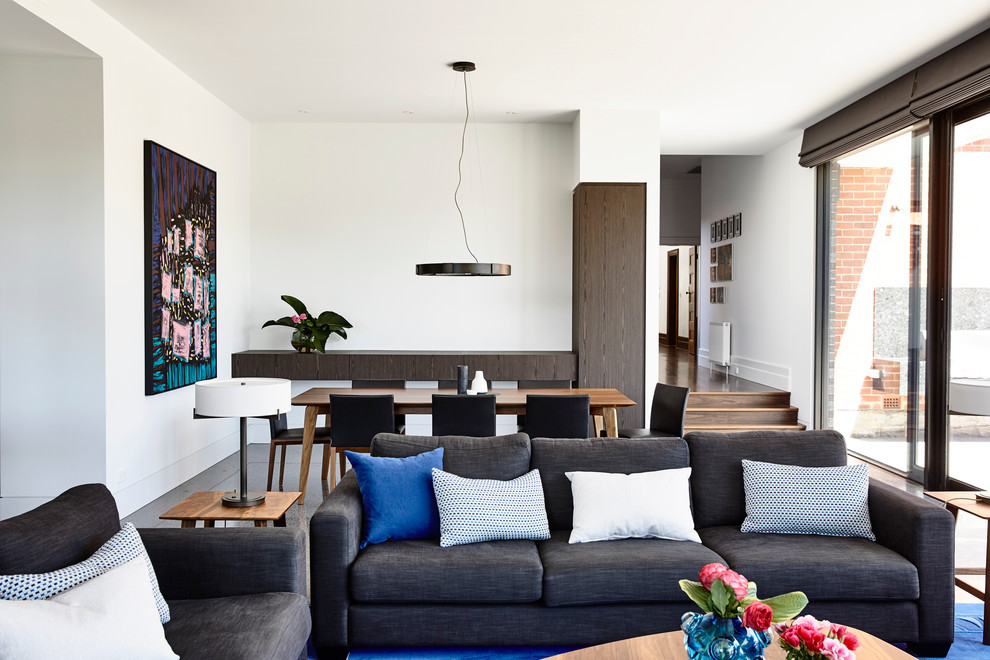 This is an example of a large contemporary open concept living room in Melbourne with white walls and concrete floors.
