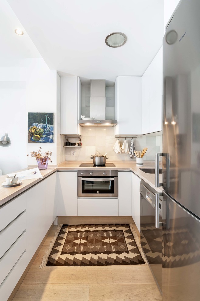 This is an example of a small beach style u-shaped separate kitchen in Seville with flat-panel cabinets, white cabinets, white splashback and no island.