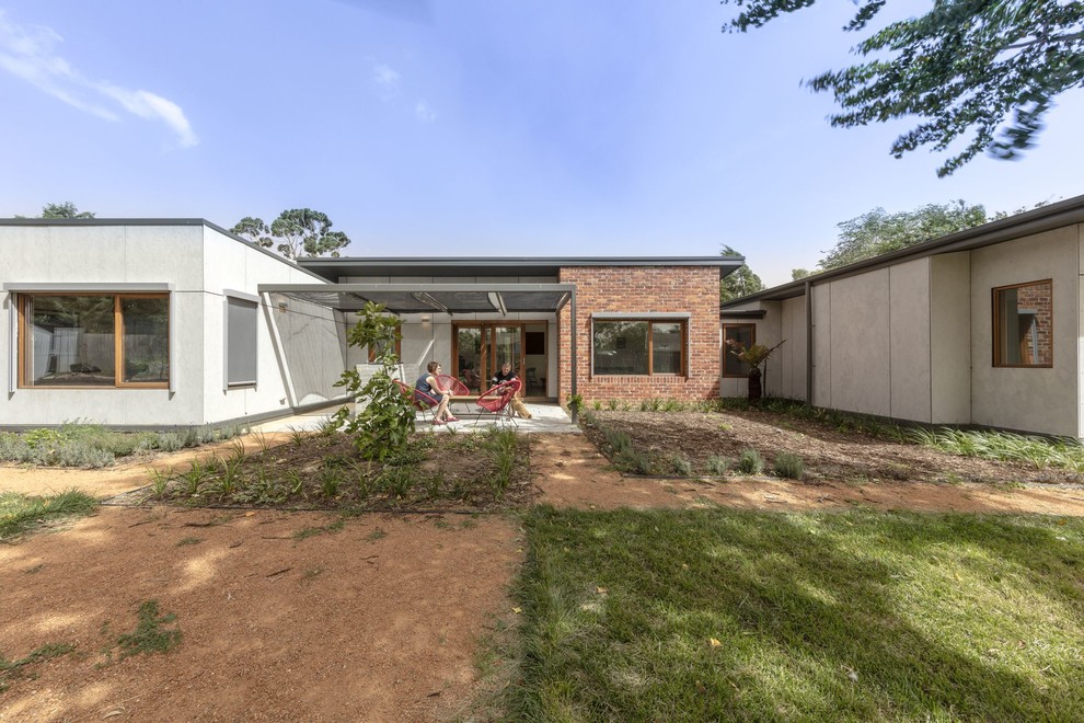 This is an example of a small contemporary one-storey grey house exterior in Canberra - Queanbeyan with a flat roof and a metal roof.