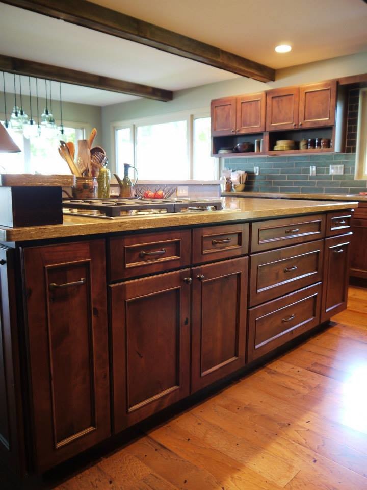 Photo of a large country open plan kitchen in Grand Rapids with an undermount sink, recessed-panel cabinets, medium wood cabinets, solid surface benchtops, green splashback, black appliances and with island.