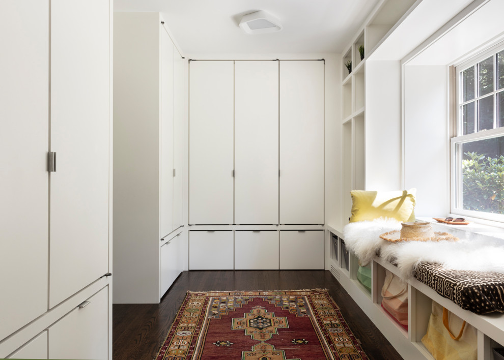 Inspiration for a large contemporary gender-neutral walk-in wardrobe in New York with flat-panel cabinets, white cabinets, dark hardwood floors and brown floor.