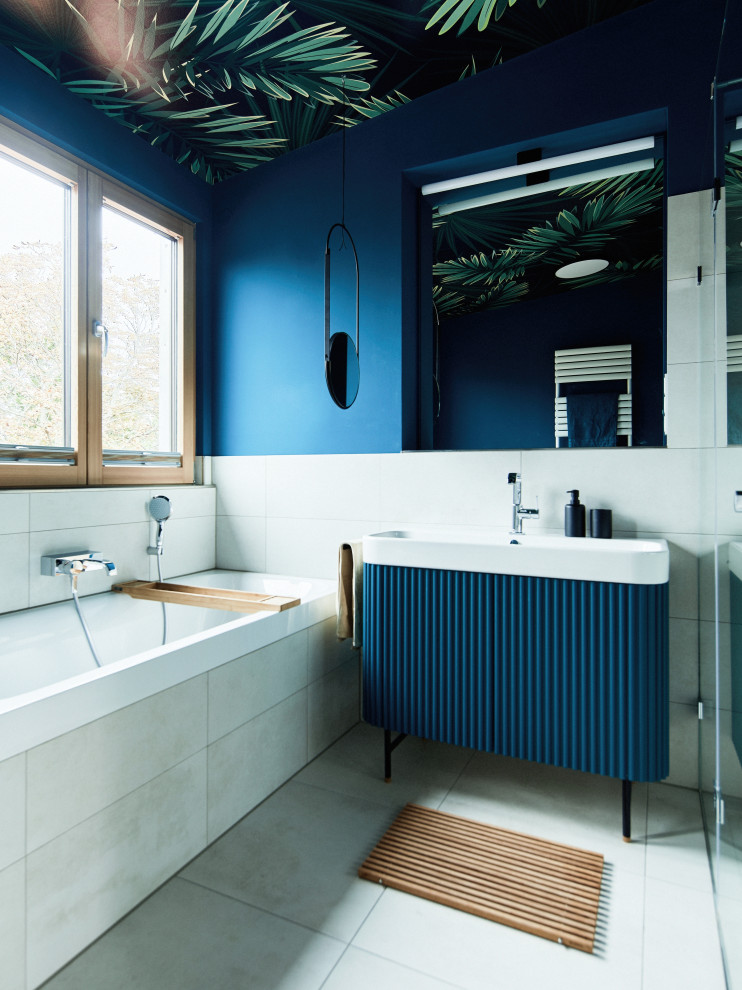 This is an example of a mid-sized eclectic bathroom in Berlin with louvered cabinets, blue cabinets, a drop-in tub, a curbless shower, a wall-mount toilet, blue walls, a vessel sink, white benchtops, a single vanity, a freestanding vanity and wallpaper.