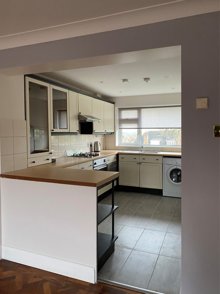 Design ideas for a small contemporary l-shaped open plan kitchen in London with an undermount sink, shaker cabinets, beige cabinets, laminate benchtops, beige splashback, ceramic splashback, stainless steel appliances, porcelain floors, a peninsula, pink floor and brown benchtop.