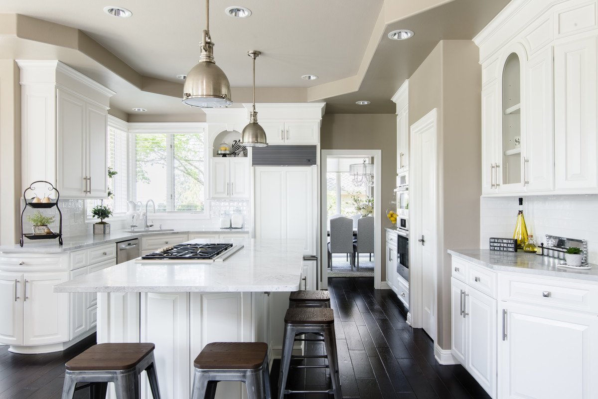 Mid-sized transitional u-shaped dark wood floor and brown floor open concept kitchen photo in Seattle with a single-bowl sink, raised-panel cabinets, white cabinets, quartzite countertops, white backsplash, ceramic backsplash, paneled appliances and an island