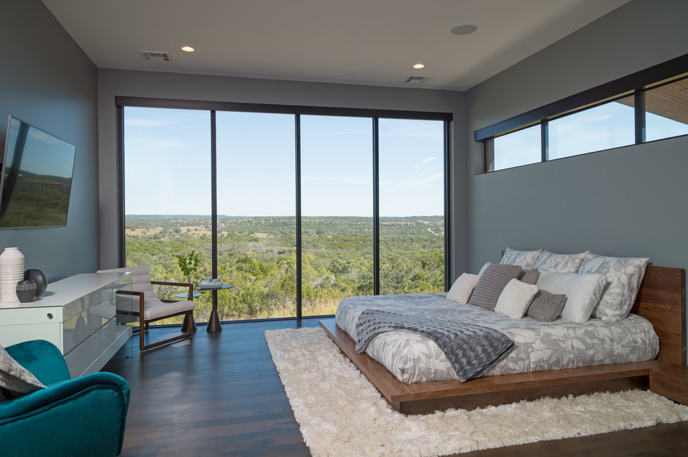 Photo of a contemporary bedroom in Austin with grey walls, dark hardwood floors and brown floor.