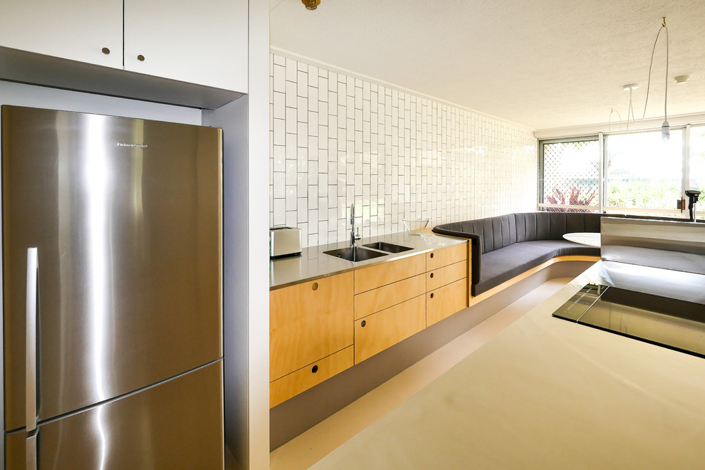 Small midcentury galley eat-in kitchen in Gold Coast - Tweed with an integrated sink, flat-panel cabinets, light wood cabinets, stainless steel benchtops, subway tile splashback, stainless steel appliances, concrete floors, no island and beige floor.