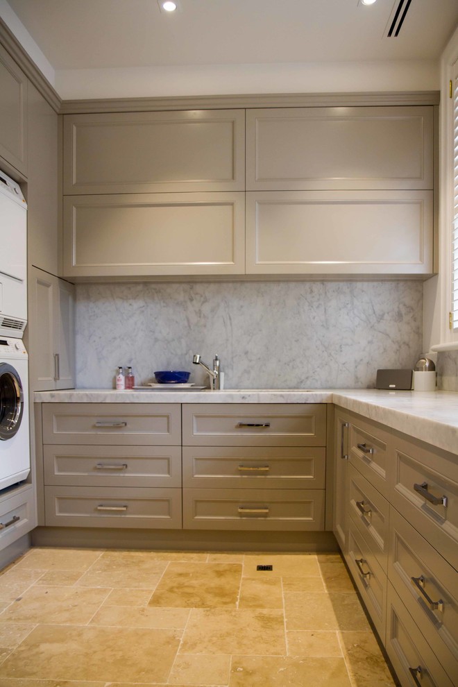 Inspiration for a large traditional u-shaped laundry room in Melbourne with shaker cabinets, marble benchtops and a stacked washer and dryer.