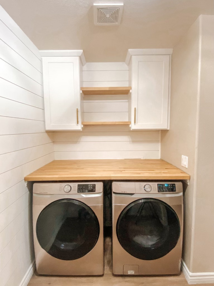 This is an example of a mid-sized traditional laundry room with shaker cabinets, white cabinets, wood benchtops, beige walls, laminate floors, a side-by-side washer and dryer, brown floor and planked wall panelling.