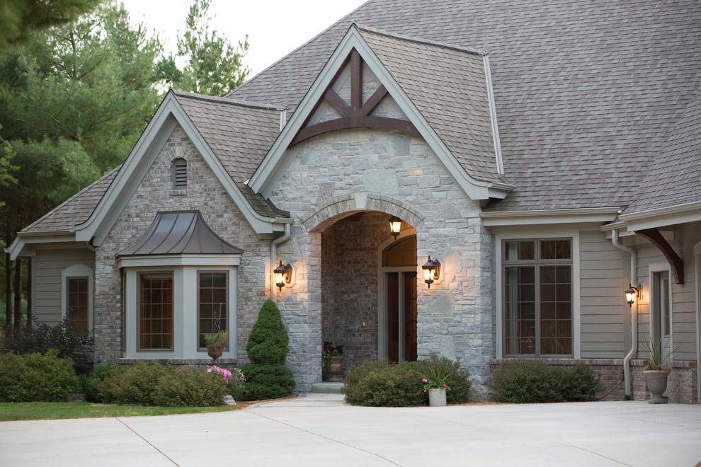 Expansive traditional one-storey beige house exterior in Milwaukee with stone veneer, a gable roof and a shingle roof.