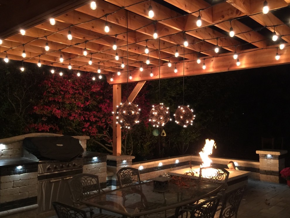 Photo of a large traditional backyard patio in Chicago with a fire feature, natural stone pavers and a pergola.