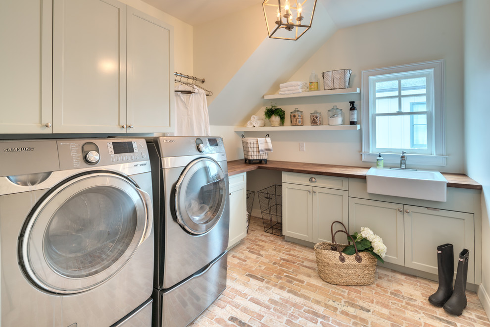Design ideas for a country l-shaped dedicated laundry room in Atlanta with a farmhouse sink, shaker cabinets, green cabinets, wood benchtops, white walls, brick floors, a side-by-side washer and dryer, brown floor and brown benchtop.