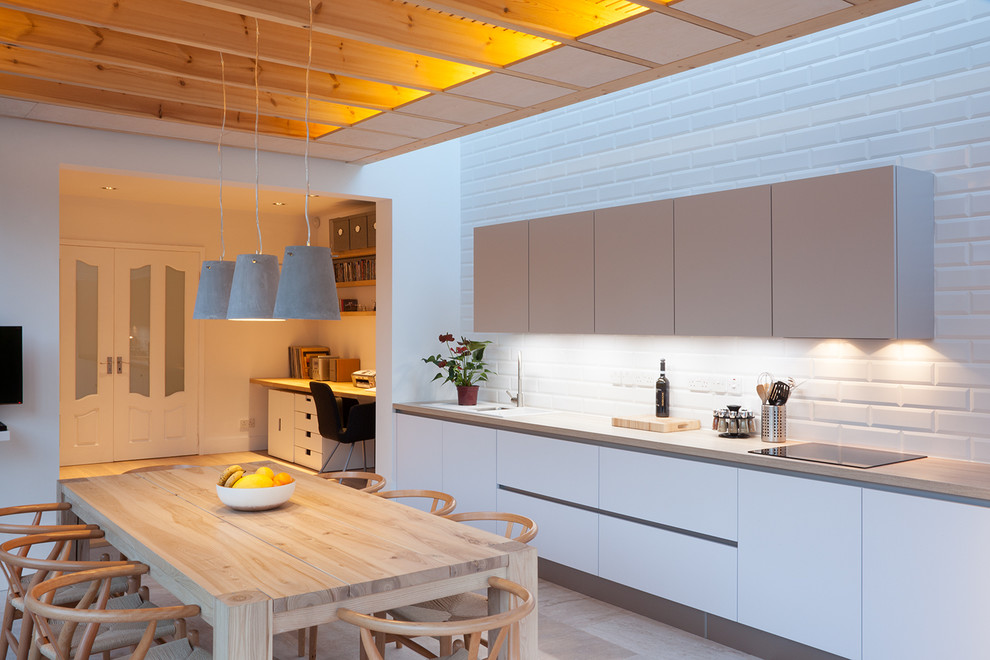 Design ideas for a medium sized contemporary single-wall kitchen/diner in Dublin with a built-in sink, flat-panel cabinets, white cabinets, laminate countertops, white splashback, ceramic splashback, porcelain flooring and no island.