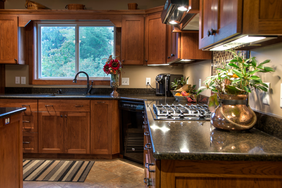Inspiration for a mid-sized rustic l-shaped kitchen remodel with an undermount sink, shaker cabinets, light wood cabinets, granite countertops, multicolored backsplash, mosaic tile backsplash, black appliances and an island