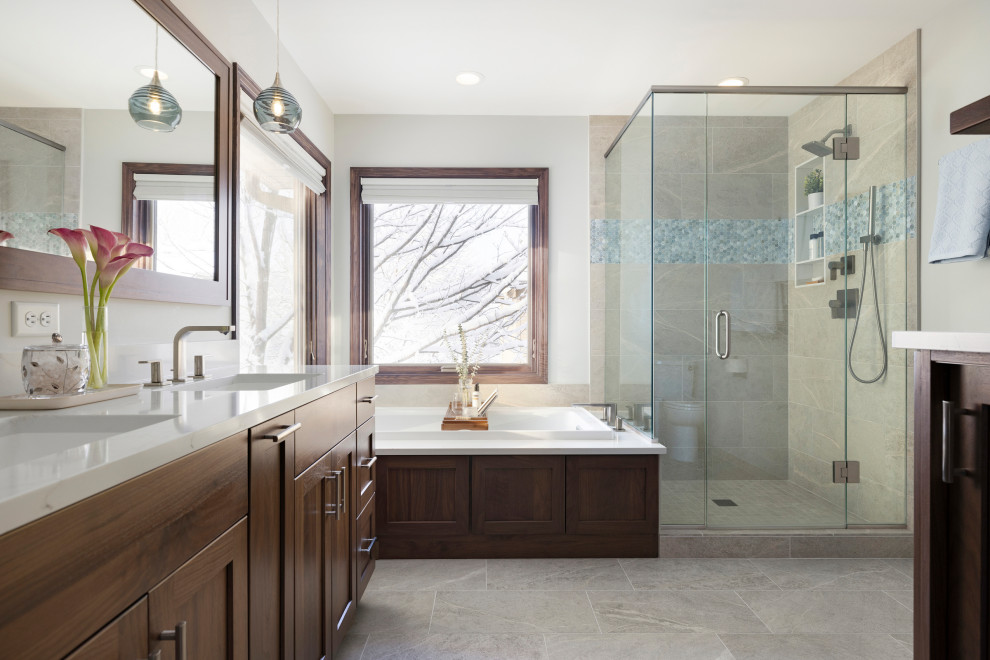 Design ideas for a medium sized contemporary ensuite bathroom in Minneapolis with recessed-panel cabinets, brown cabinets, a built-in bath, a corner shower, a two-piece toilet, beige walls, a submerged sink, engineered stone worktops, beige floors, a hinged door, white worktops, double sinks and a freestanding vanity unit.