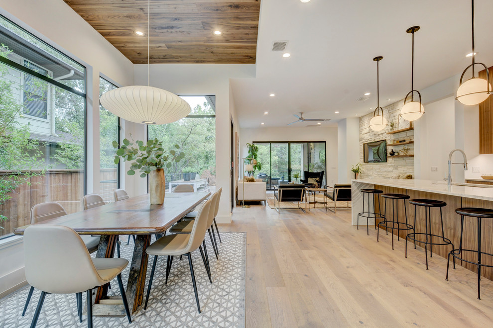 Contemporary open plan dining in Austin with white walls, light hardwood floors and beige floor.