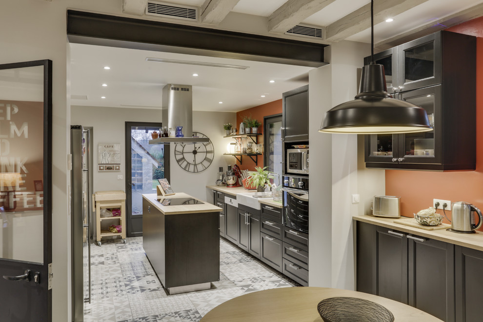 Inspiration for an expansive transitional galley open plan kitchen in Paris with a drop-in sink, flat-panel cabinets, black cabinets, wood benchtops, stainless steel appliances, cement tiles, with island and multi-coloured floor.