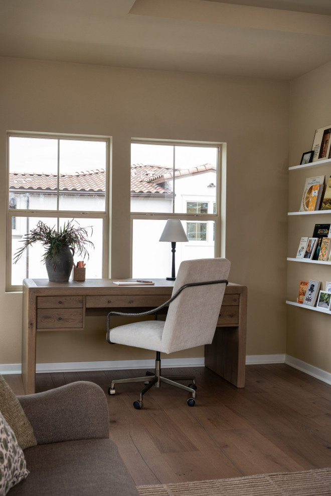 Example of a tuscan freestanding desk medium tone wood floor and brown floor home office design in Los Angeles with beige walls
