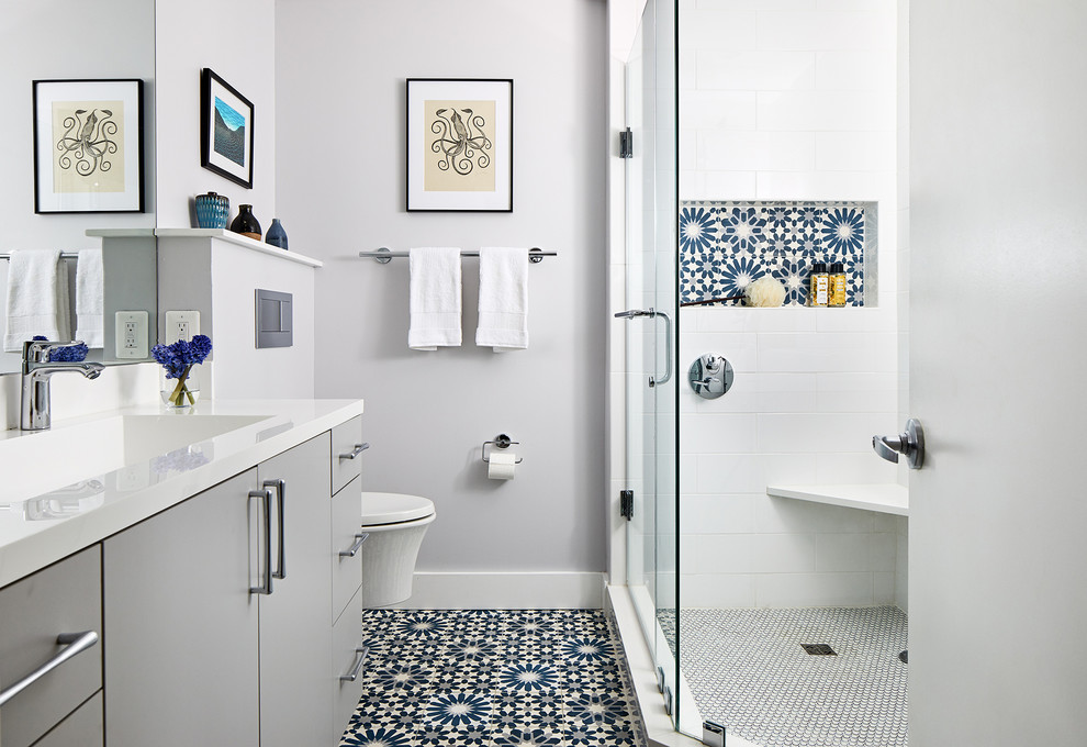 Mid-sized contemporary master bathroom in DC Metro with flat-panel cabinets, grey cabinets, a corner shower, a wall-mount toilet, white tile, grey walls, a hinged shower door and white benchtops.