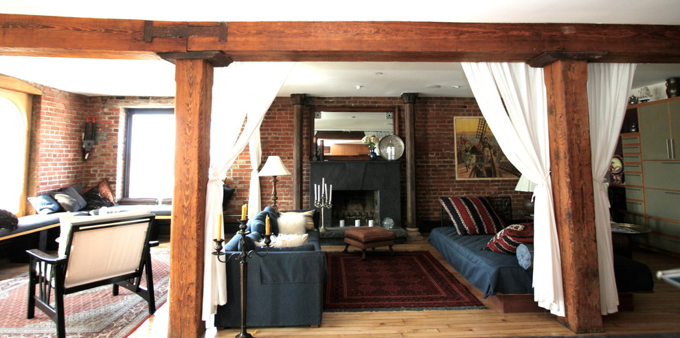 This is an example of a mid-sized eclectic loft-style living room in New York with brown walls, light hardwood floors, a standard fireplace, a stone fireplace surround and no tv.