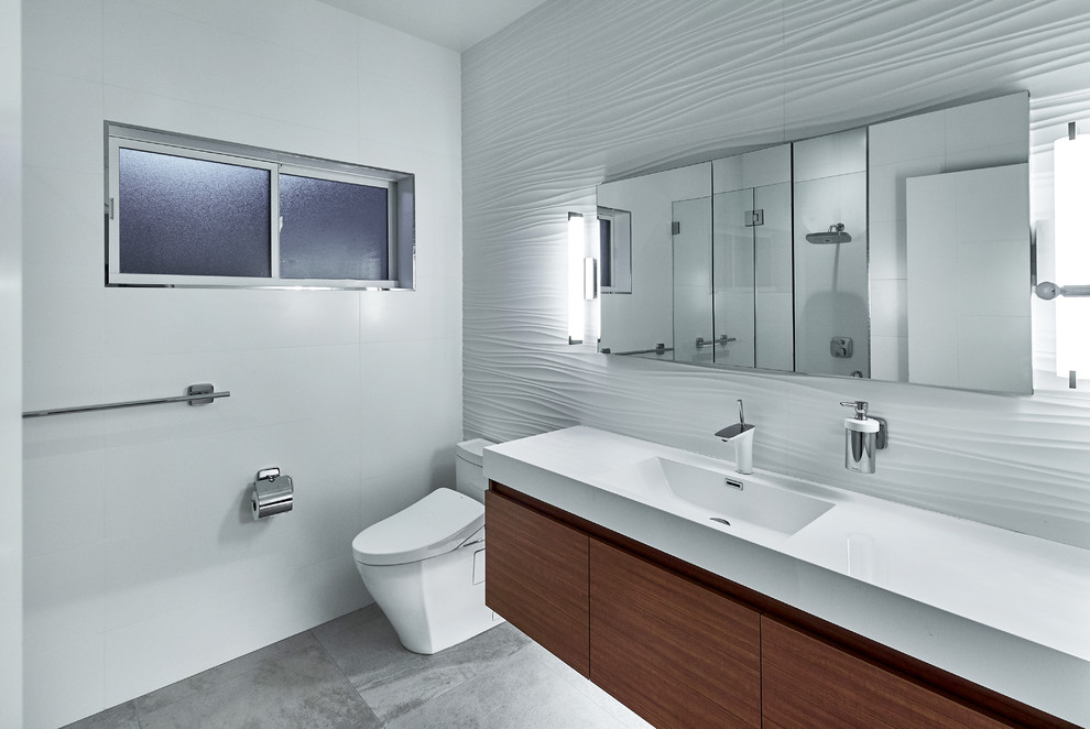Inspiration for a mid-sized contemporary 3/4 bathroom in San Francisco with flat-panel cabinets, dark wood cabinets, an alcove shower, white tile, grey walls, concrete floors, an integrated sink, solid surface benchtops, grey floor, a hinged shower door and white benchtops.