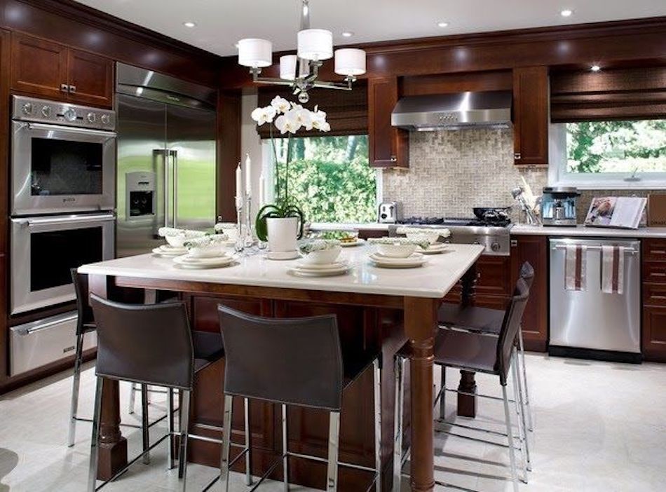 Inspiration for a large modern l-shaped gray floor enclosed kitchen remodel in Las Vegas with shaker cabinets, dark wood cabinets, solid surface countertops, beige backsplash, stainless steel appliances, an island and beige countertops