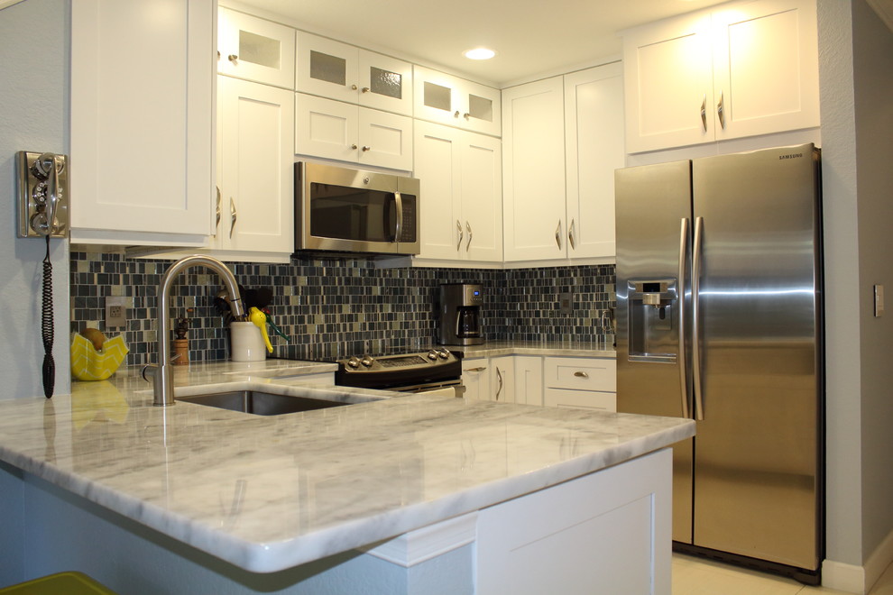Enclosed kitchen - mid-sized transitional u-shaped porcelain tile and white floor enclosed kitchen idea in Miami with an undermount sink, shaker cabinets, white cabinets, quartzite countertops, gray backsplash, glass tile backsplash, stainless steel appliances and no island
