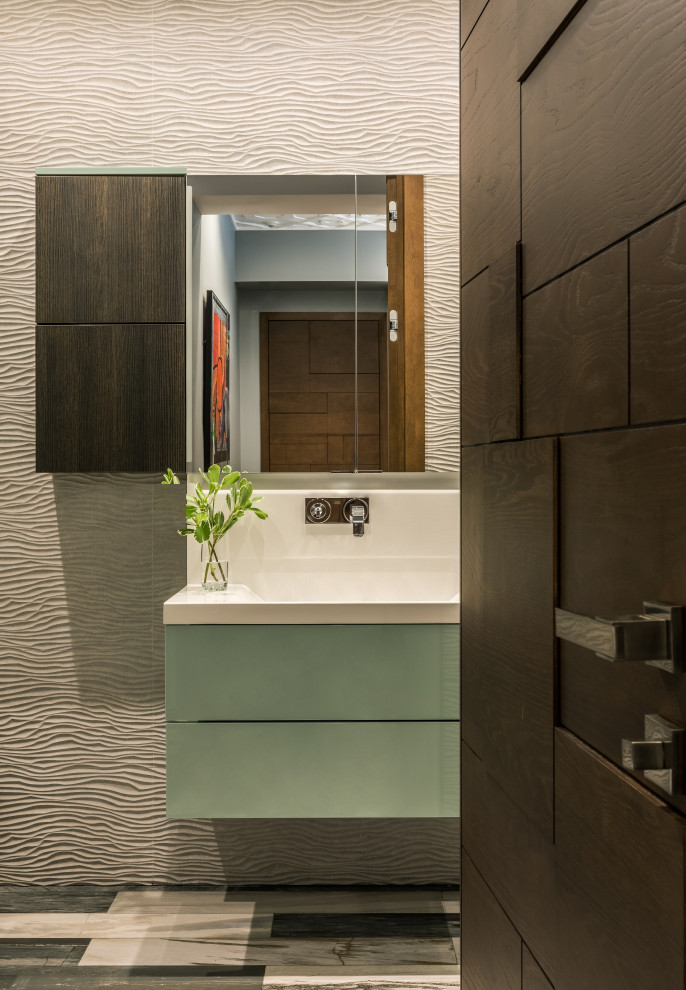 Small contemporary powder room in Moscow with turquoise cabinets, a wall-mount toilet, beige tile, porcelain tile, beige walls, ceramic floors, a wall-mount sink, solid surface benchtops, multi-coloured floor and white benchtops.