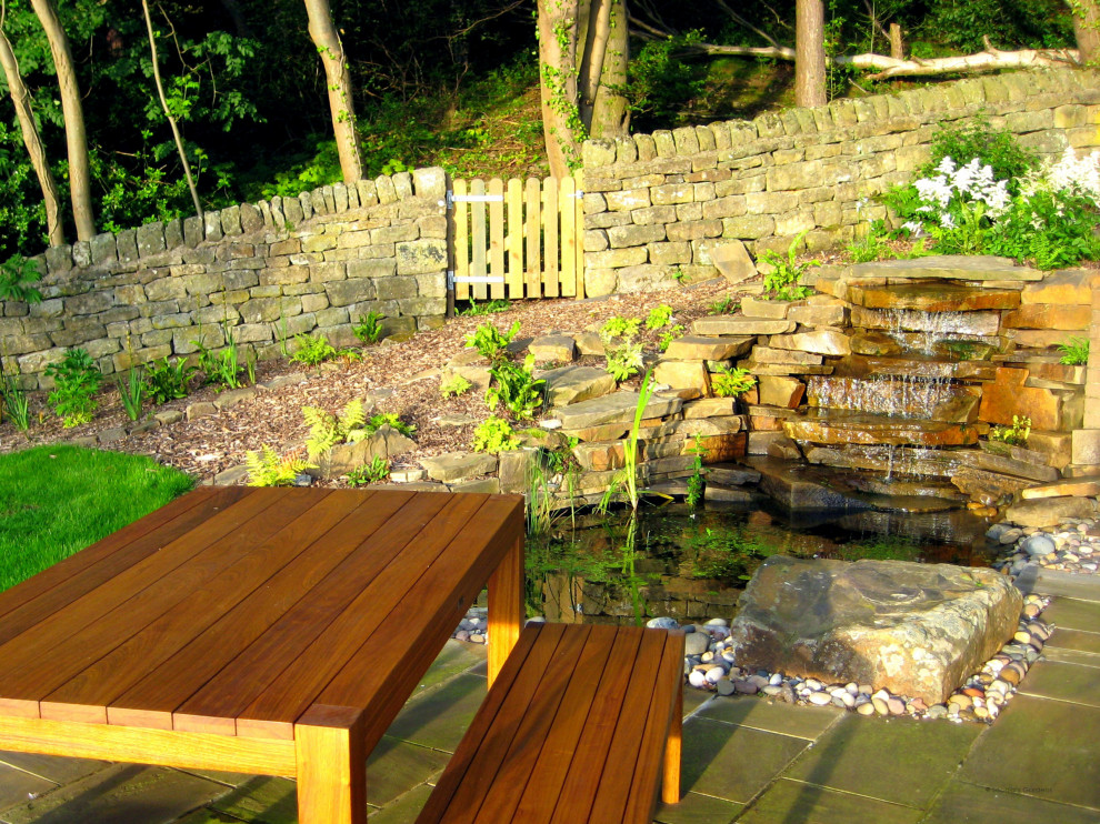 Large country sloped partial sun garden in Other with with waterfall and natural stone pavers for spring.