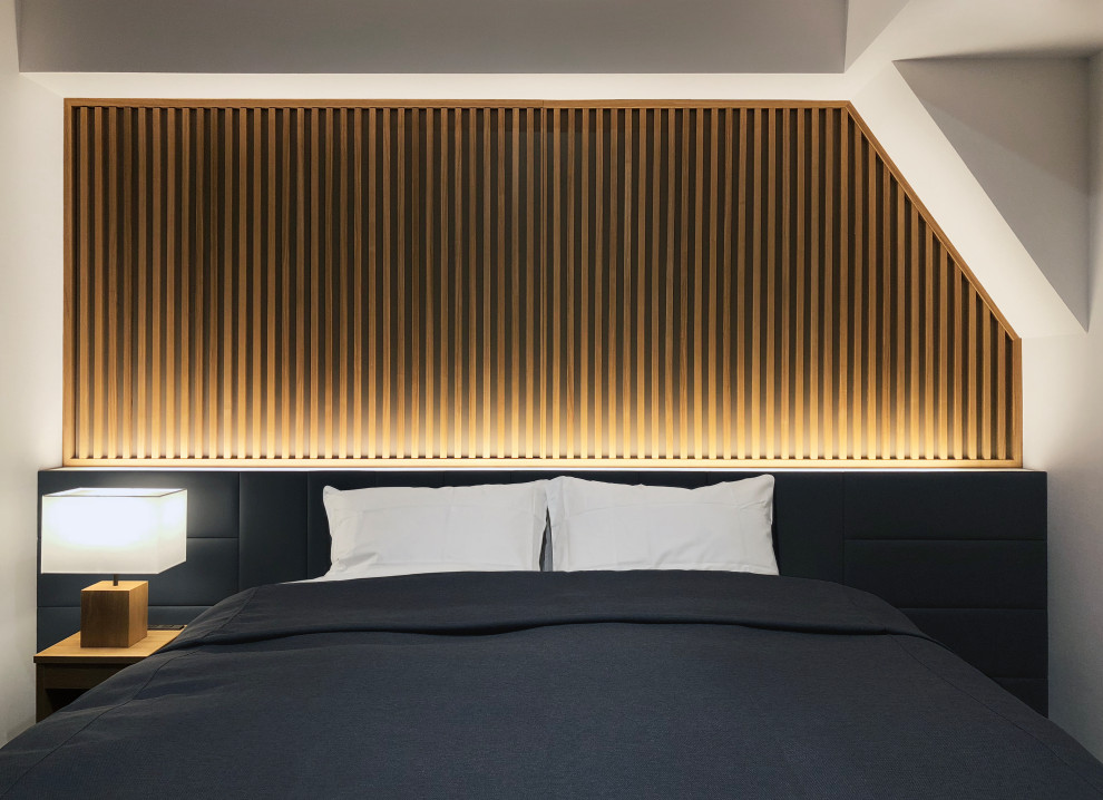 Bild på ett skandinaviskt sovrum, med vita väggar, heltäckningsmatta och grått golv