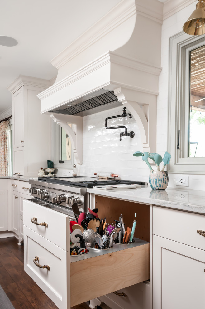 Photo of a mid-sized traditional kitchen in Atlanta with a farmhouse sink, shaker cabinets, white cabinets, quartzite benchtops, white splashback, mosaic tile splashback, stainless steel appliances, medium hardwood floors, with island, brown floor and white benchtop.