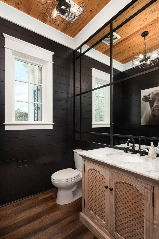 Inspiration for a country powder room in Atlanta with recessed-panel cabinets, light wood cabinets, black walls, dark hardwood floors, an undermount sink, brown floor, white benchtops, a built-in vanity and planked wall panelling.