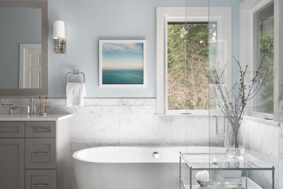 This is an example of a mid-sized transitional master bathroom with shaker cabinets, grey cabinets, a freestanding tub, an open shower, a two-piece toilet, white tile, marble, grey walls, marble floors, an undermount sink, engineered quartz benchtops, white floor, an open shower and white benchtops.