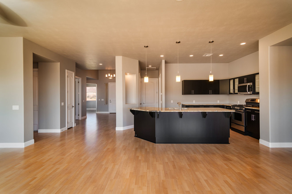 This is an example of a large contemporary l-shaped open plan kitchen in Salt Lake City with a double-bowl sink, flat-panel cabinets, black cabinets, granite benchtops, stainless steel appliances, vinyl floors and with island.