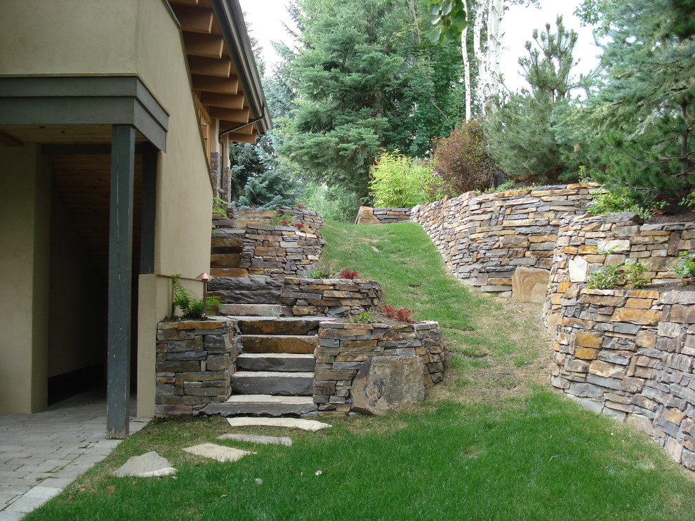 Inspiration for a mid-sized traditional backyard partial sun formal garden for spring in Boise with a retaining wall and natural stone pavers.