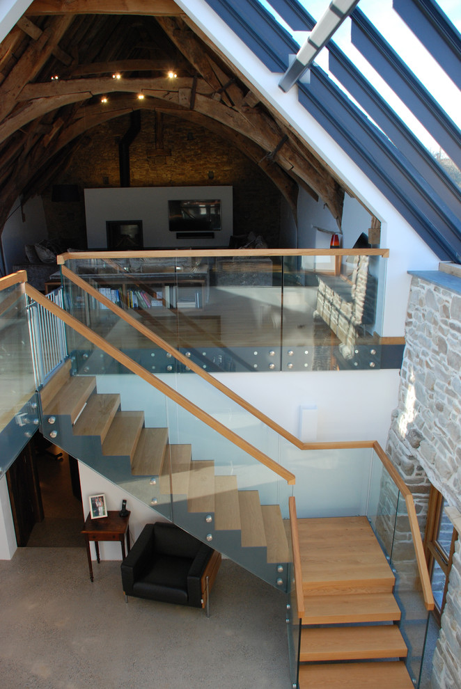 Photo of an expansive contemporary wood l-shaped staircase in Cornwall with open risers and wood railing.