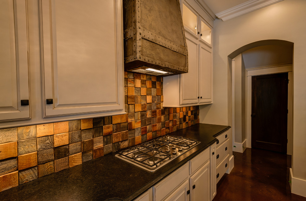 Example of a transitional concrete floor kitchen design with a farmhouse sink, raised-panel cabinets, black cabinets, granite countertops and an island