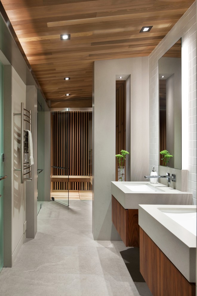 This is an example of a contemporary bathroom in Vancouver with porcelain floors, flat-panel cabinets, medium wood cabinets, an alcove shower, white tile, subway tile, an undermount sink, grey floor and a hinged shower door.