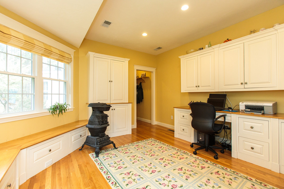 Photo of a mid-sized traditional study room in Boston with yellow walls, medium hardwood floors and a built-in desk.