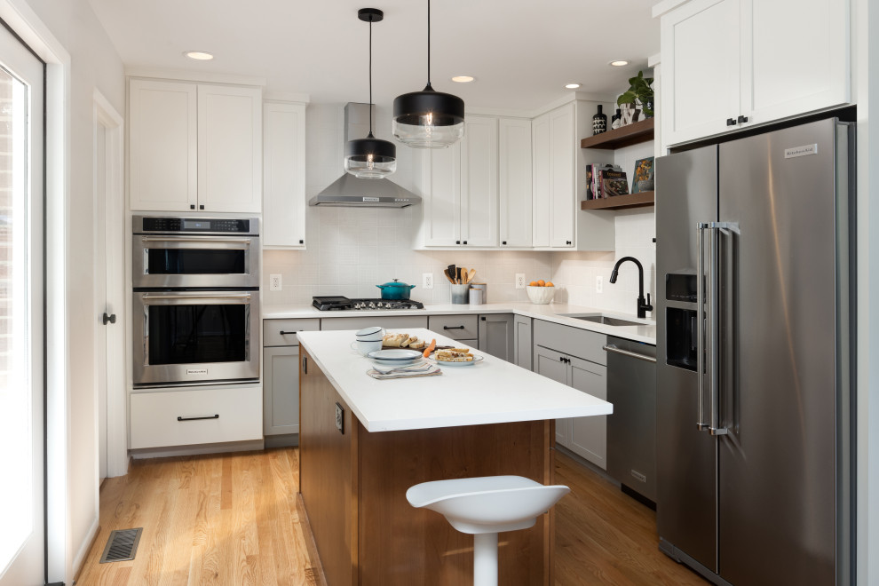 Exempel på ett mellanstort klassiskt vit vitt kök, med en undermonterad diskho, skåp i shakerstil, vita skåp, bänkskiva i kvarts, vitt stänkskydd, stänkskydd i keramik, rostfria vitvaror, mellanmörkt trägolv, en köksö och brunt golv