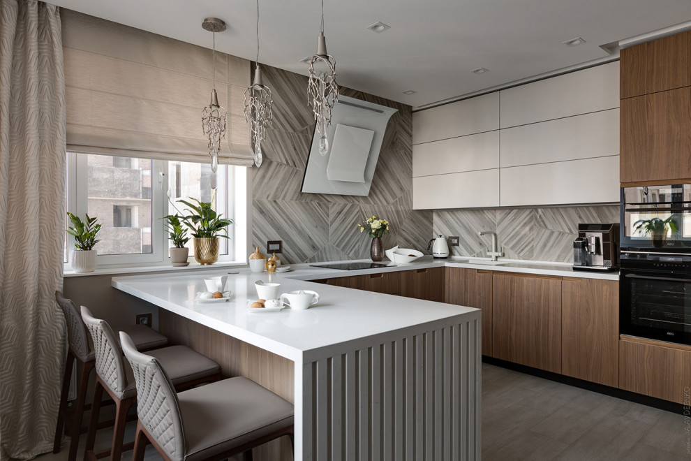 This is an example of a mid-sized contemporary u-shaped kitchen in Other with an integrated sink, flat-panel cabinets, medium wood cabinets, grey splashback, black appliances, a peninsula, grey floor and white benchtop.