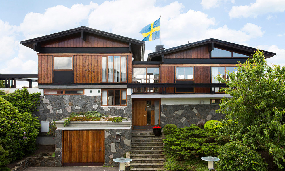 This is an example of an expansive transitional two-storey brown exterior in Stockholm with wood siding and a gable roof.