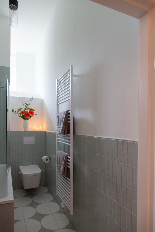 This is an example of a mid-sized contemporary 3/4 bathroom in Berlin with raised-panel cabinets, grey cabinets, a drop-in tub, a shower/bathtub combo, a two-piece toilet, green tile, ceramic tile, white walls, ceramic floors, an integrated sink, laminate benchtops, grey floor, an open shower, white benchtops, a single vanity, a floating vanity and recessed.