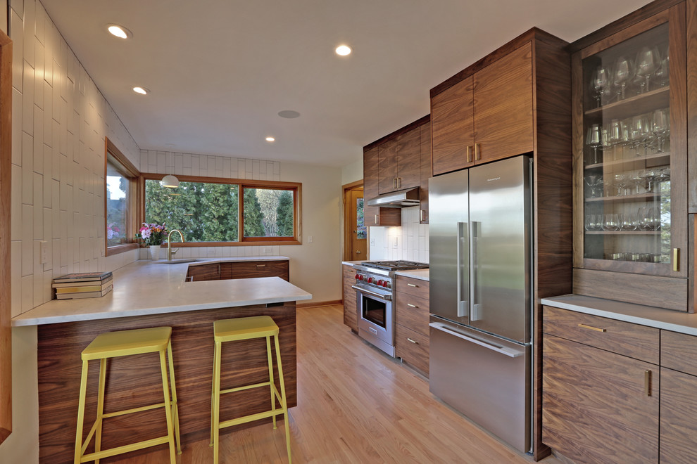 Design ideas for a mid-sized midcentury galley open plan kitchen in Portland with an undermount sink, flat-panel cabinets, dark wood cabinets, marble benchtops, white splashback, subway tile splashback, stainless steel appliances, medium hardwood floors, a peninsula and beige floor.