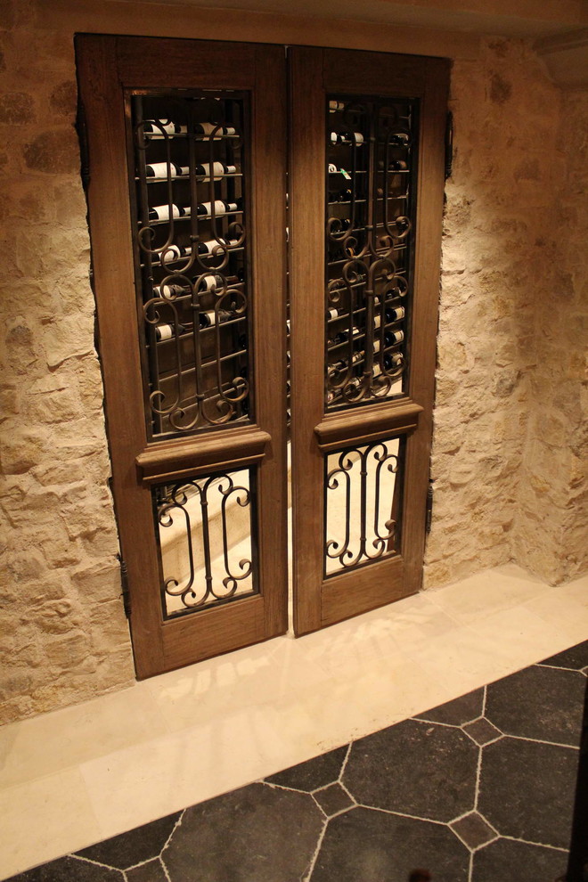 Large mediterranean wine cellar in Other with limestone floors and display racks.