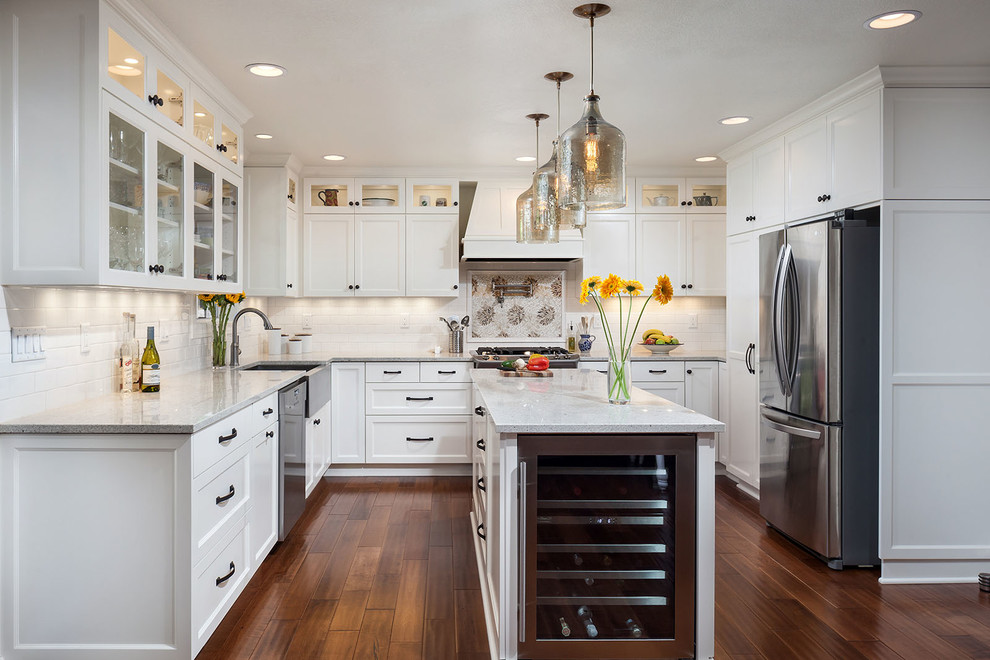 Traditional u-shaped kitchen in Portland with a farmhouse sink, shaker cabinets, white cabinets, white splashback, subway tile splashback, stainless steel appliances, dark hardwood floors and with island.