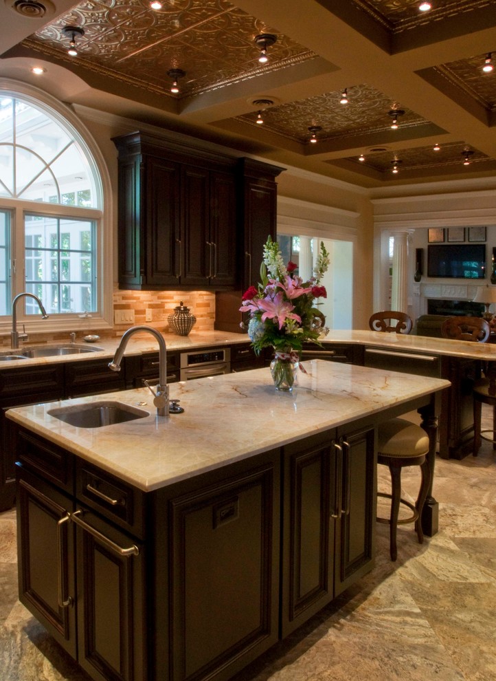 Design ideas for a large traditional u-shaped open plan kitchen in Tampa with a double-bowl sink, recessed-panel cabinets, dark wood cabinets, marble benchtops, beige splashback, porcelain splashback, stainless steel appliances, ceramic floors, with island and brown floor.